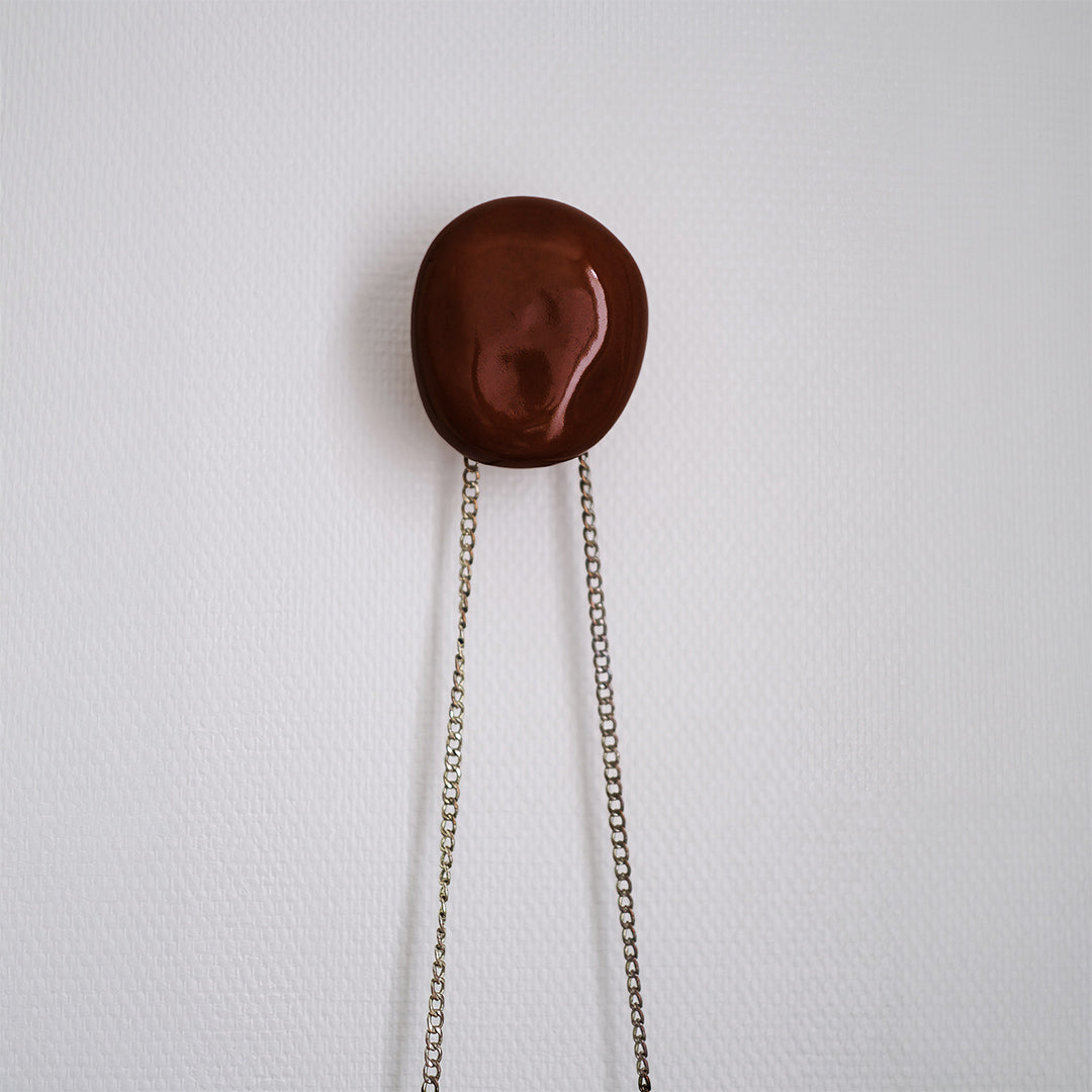 patère Agate couleur grenat en porcelaine émaillée, installée sur un mur blanc vue de face #couleur_grenat
