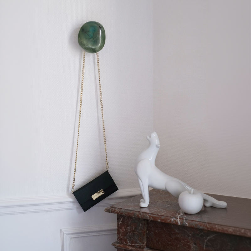 Patère murale en porcelaine cristallisée verte avec sac à main suspendu dans un intérieur haussmannien.