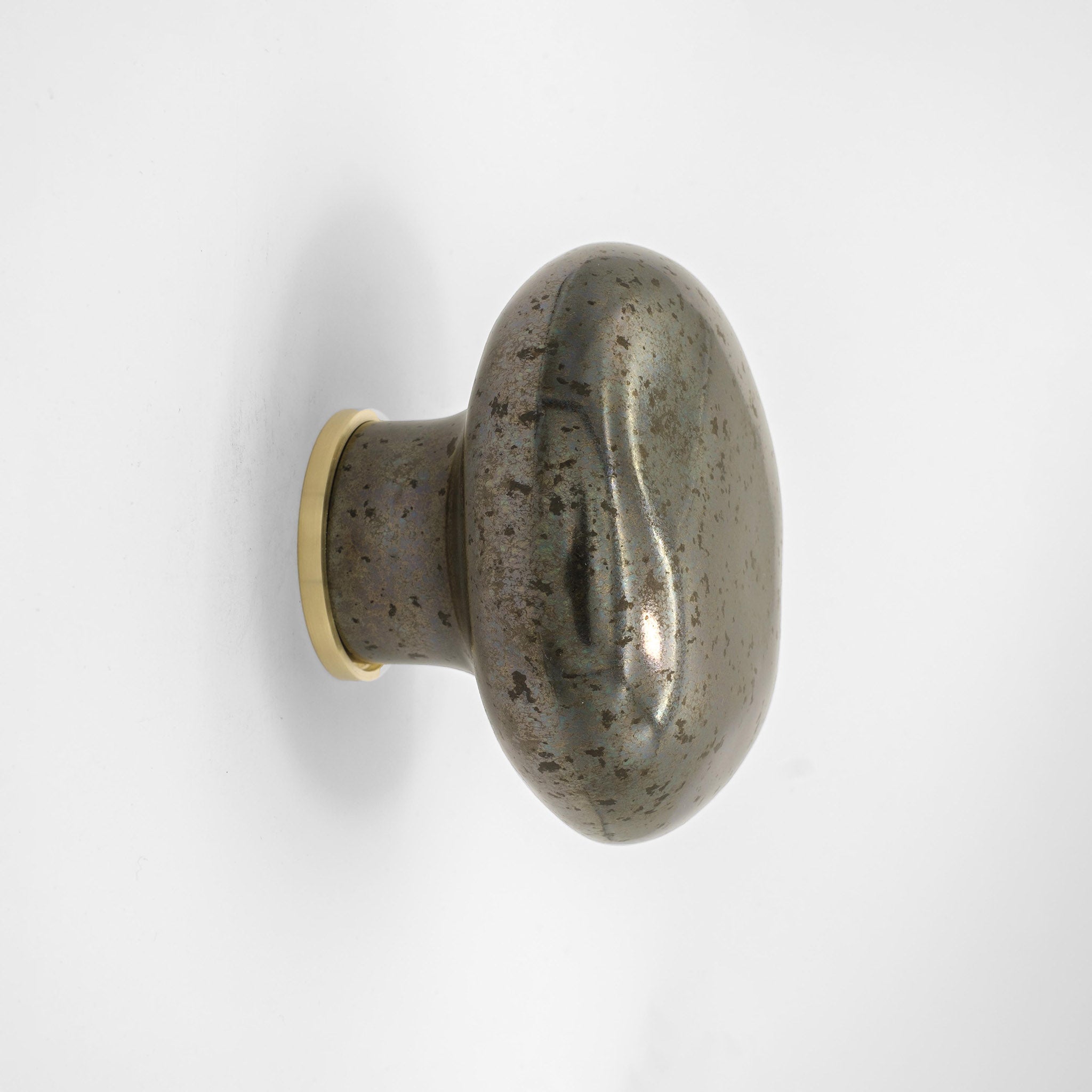 patère Agate métallique en porcelaine émaillée, installée sur un mur blanc et vue de profil #couleur_métallique