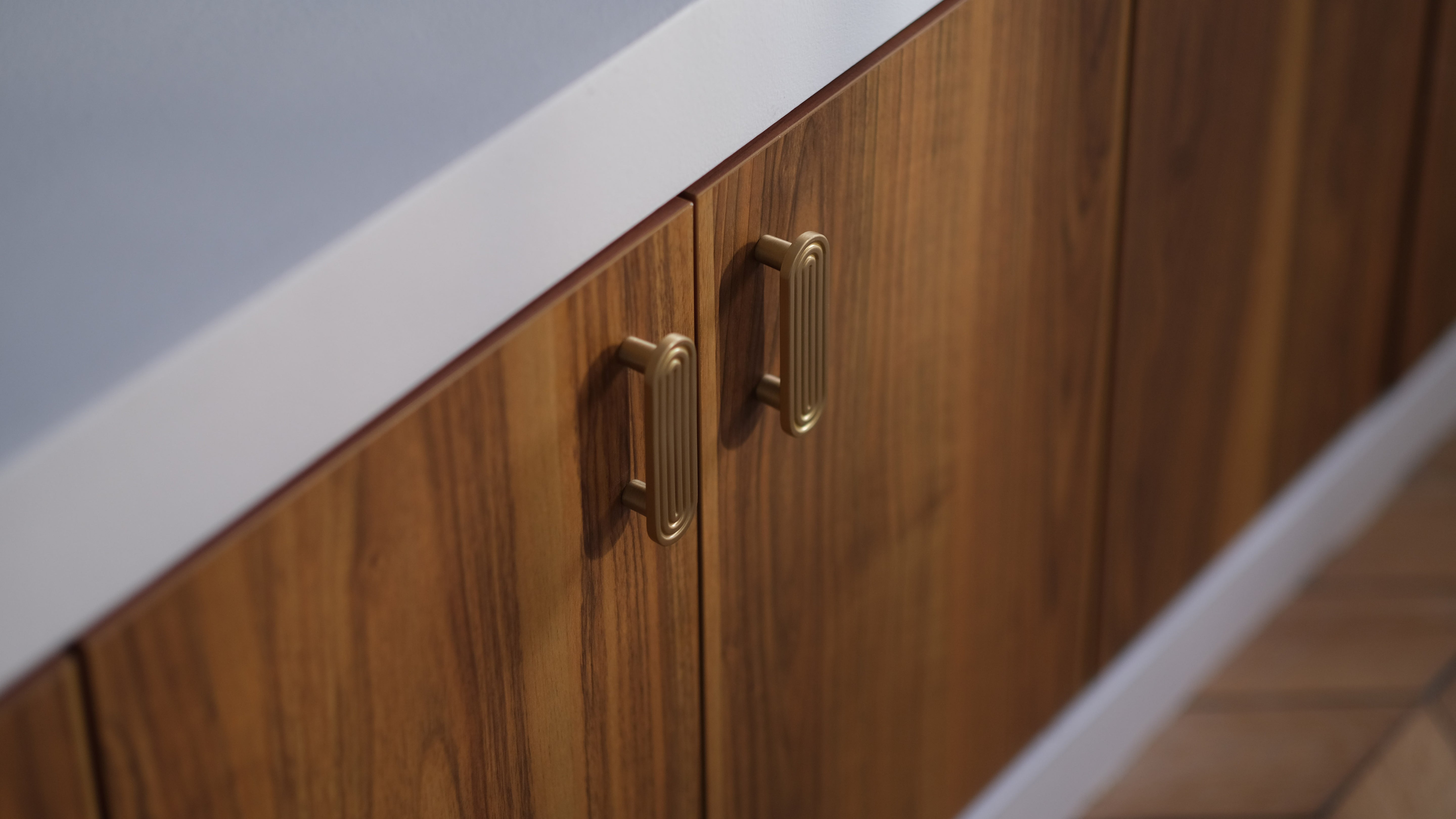 Détail de poignées en laiton doré sur mobilier crée sur mesure en bois foncé dans un projet de design intérieur haut de gamme.