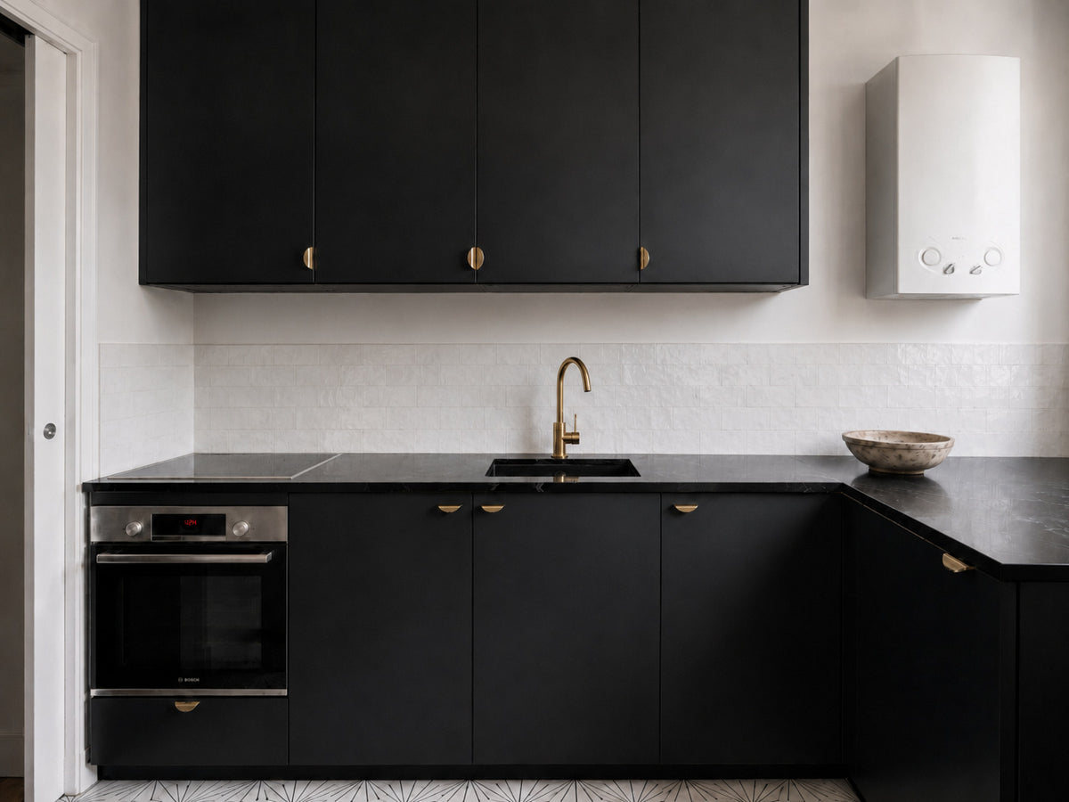 Cuisine noire et blanche rénovée dans un appartement haussmannien parisien avec design minimaliste et matériaux contrastés.