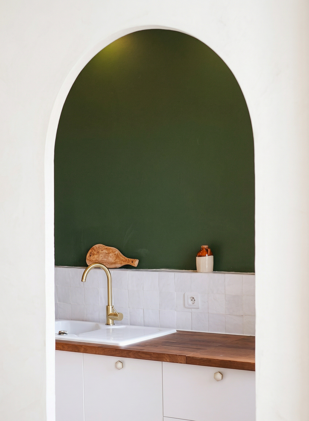 Design d'espace d’un appartement à Nice avec arche maçonnée donnant sur une cuisine sur mesure aux lignes épurées.