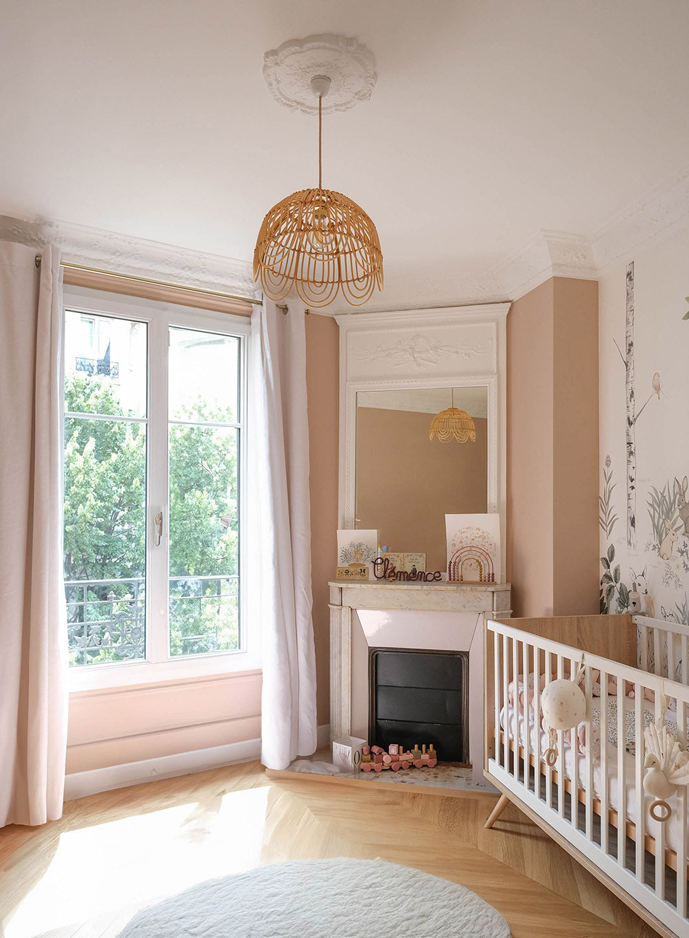 Chambre bébé dans un appartement parisien rénové avec décoration intérieure douce, cheminée ancienne et parquet point de Hongrie.