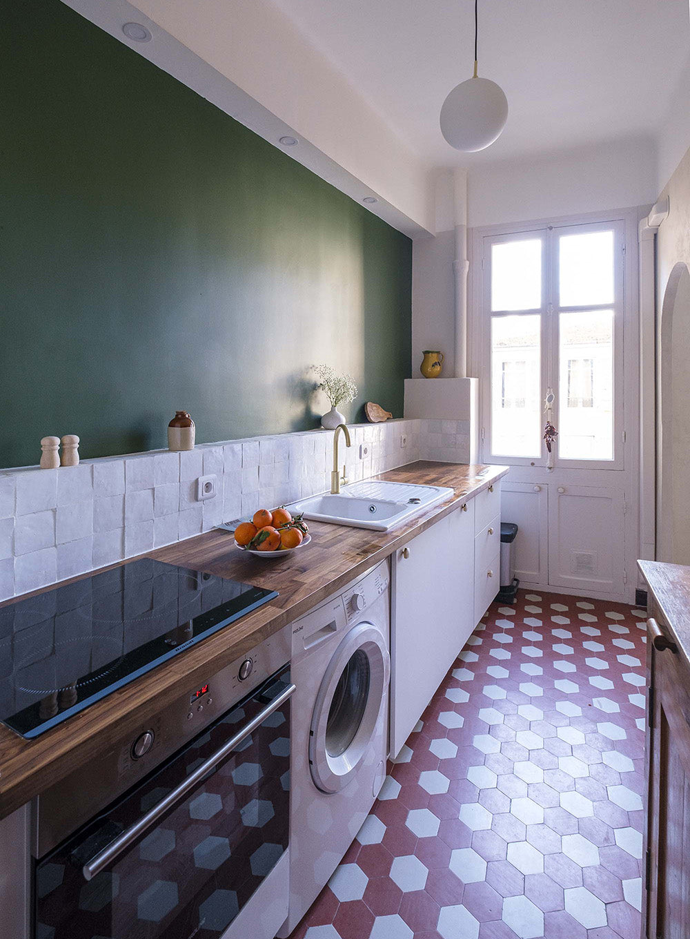 Cuisine étroite optimisée, crédence en zellige et mur vert profond, aux inspirations méditerranéennes. Projet d'architecture d'intérieur à Nice.