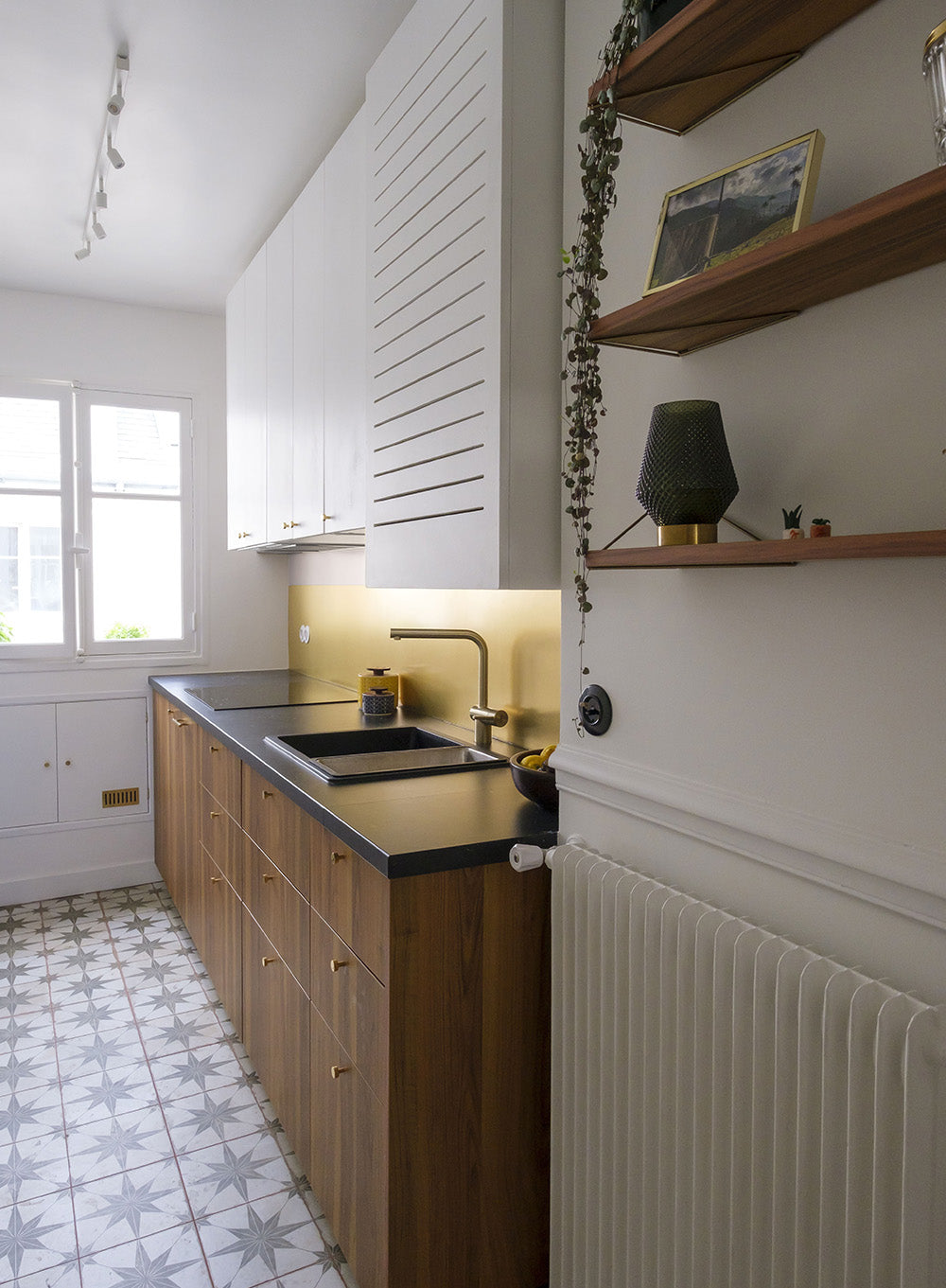 Cuisine rénovée dans un appartement parisien avec meubles en bois foncé, plan de travail noir et design intérieur contemporain.
