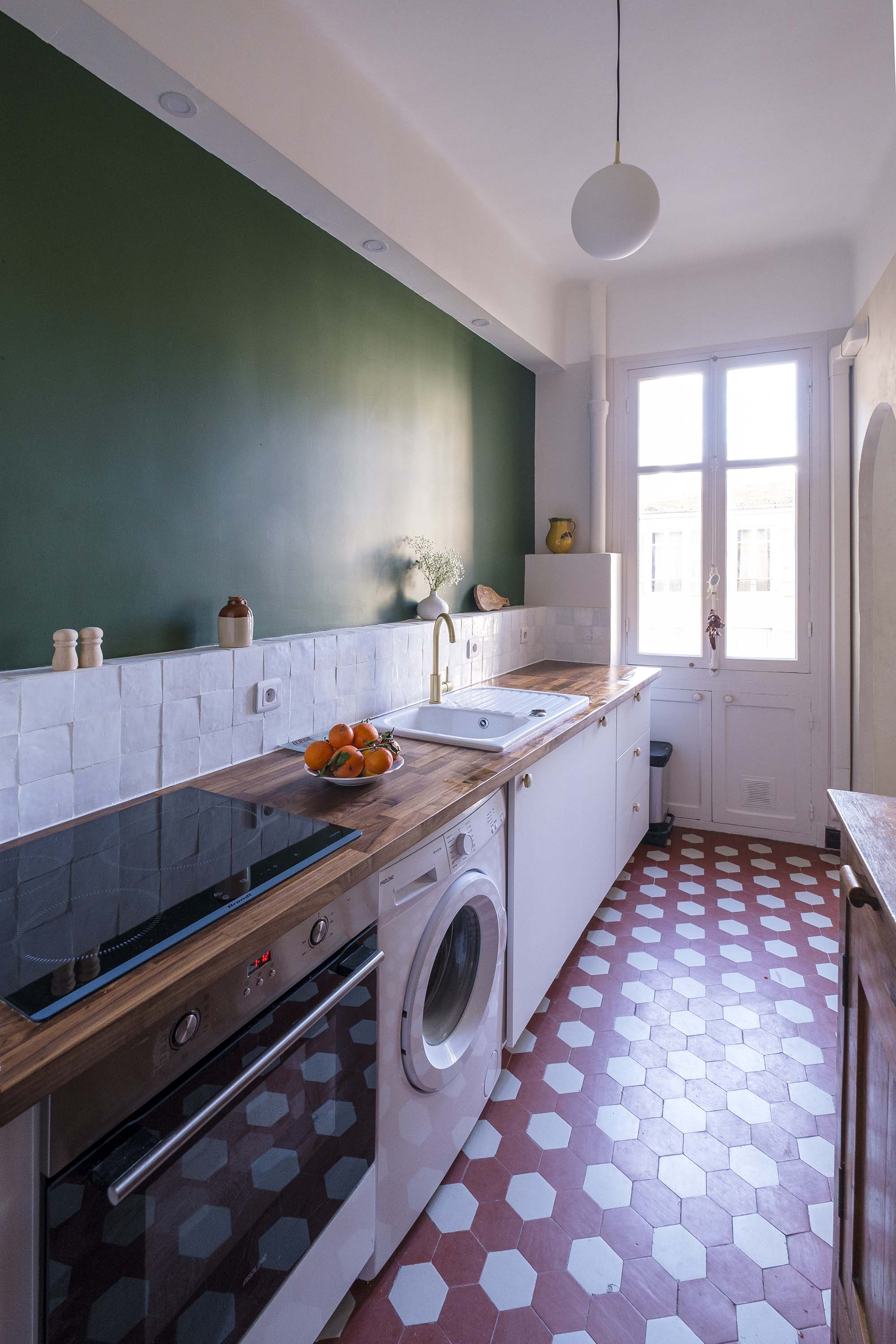 Rénovation d’un appartement à Nice avec cuisine étroite optimisée, crédence en zellige et mur vert profond, aux inspirations méditerranéennes.