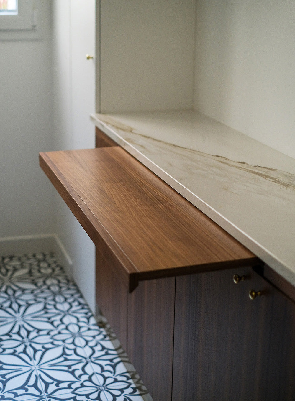 Design d’espace sur mesure à Saint Mandé avec cuisine en noyer avec tablette rétractable, plan de travail effet marbre et détails en laiton doré pour un projet de rénovation haut de gamme.