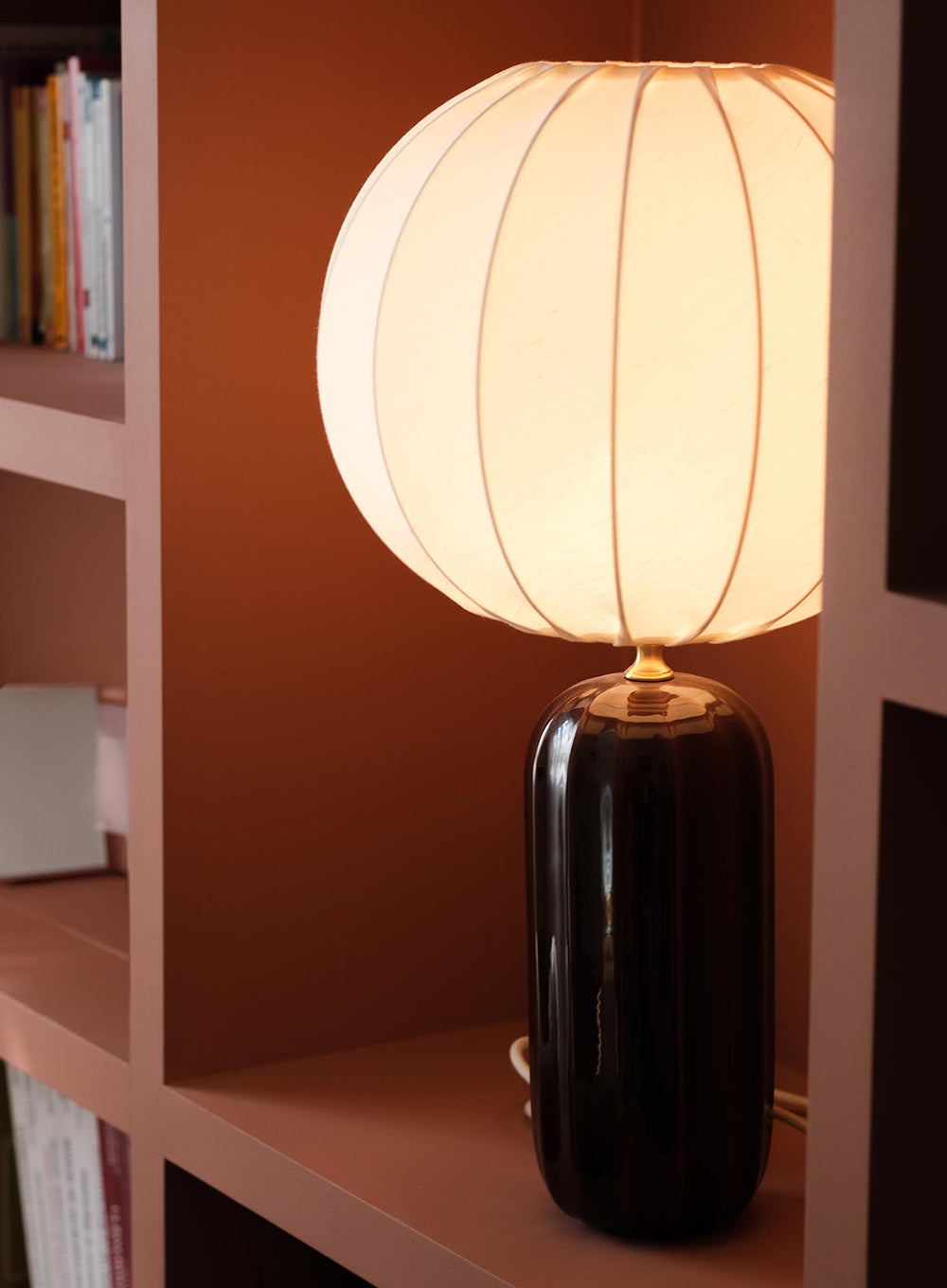 Lampe design crée par Ombre d'Or, bibliothèque terracotta et composition intérieure chaleureuse imaginées pour la salle de consultation d'un appartement rénové en cabinet de psychologie contemporain à Paris.