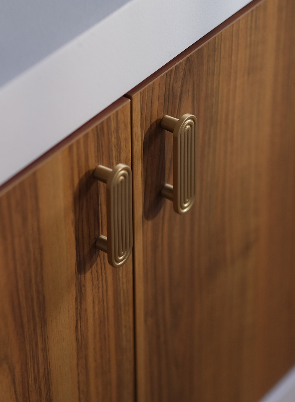 Détail de poignées en laiton doré sur mobilier crée sur mesure en bois foncé dans un projet de design intérieur haut de gamme.
