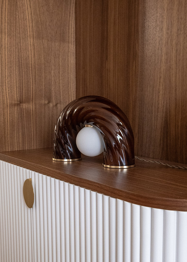 Détail de décoration intérieure au projet de Saint Mandé avec luminaire sculptural en céramique marron et bibliothèque sur mesure aux finitions texturées.