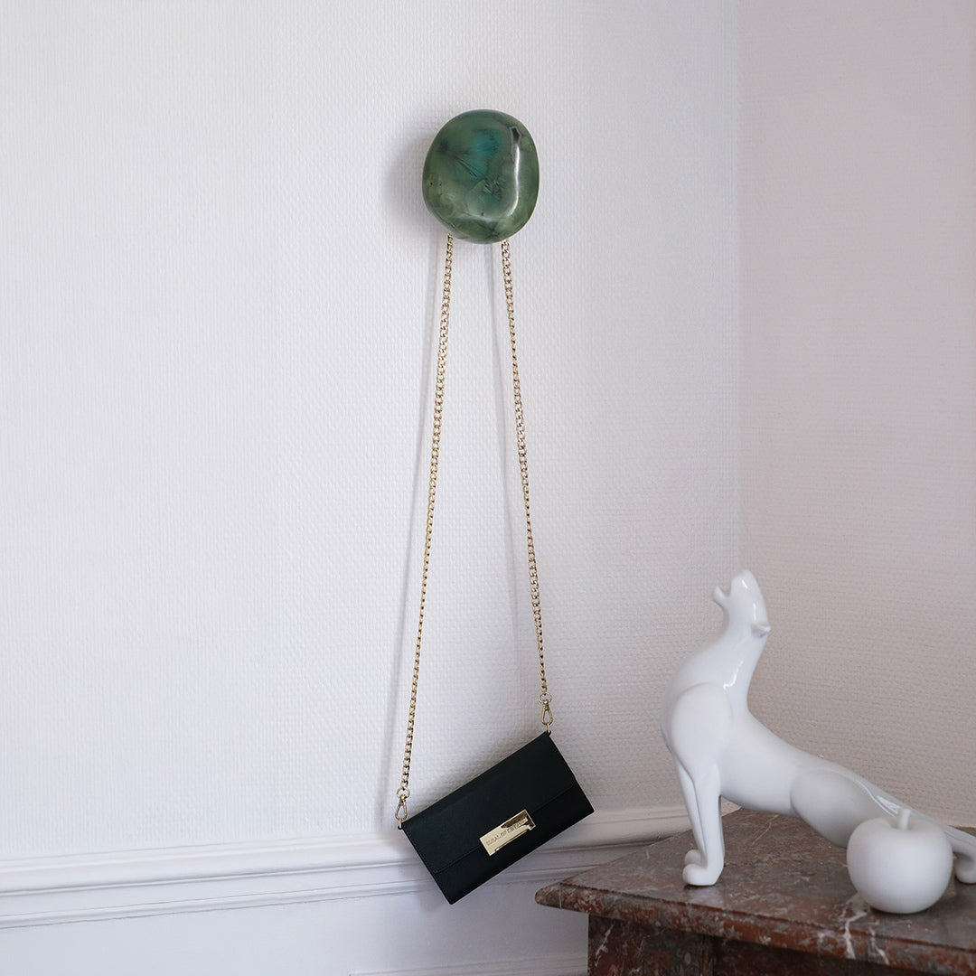 Patère murale en porcelaine cristallisée verte avec sac à main suspendu dans un intérieur haussmannien.