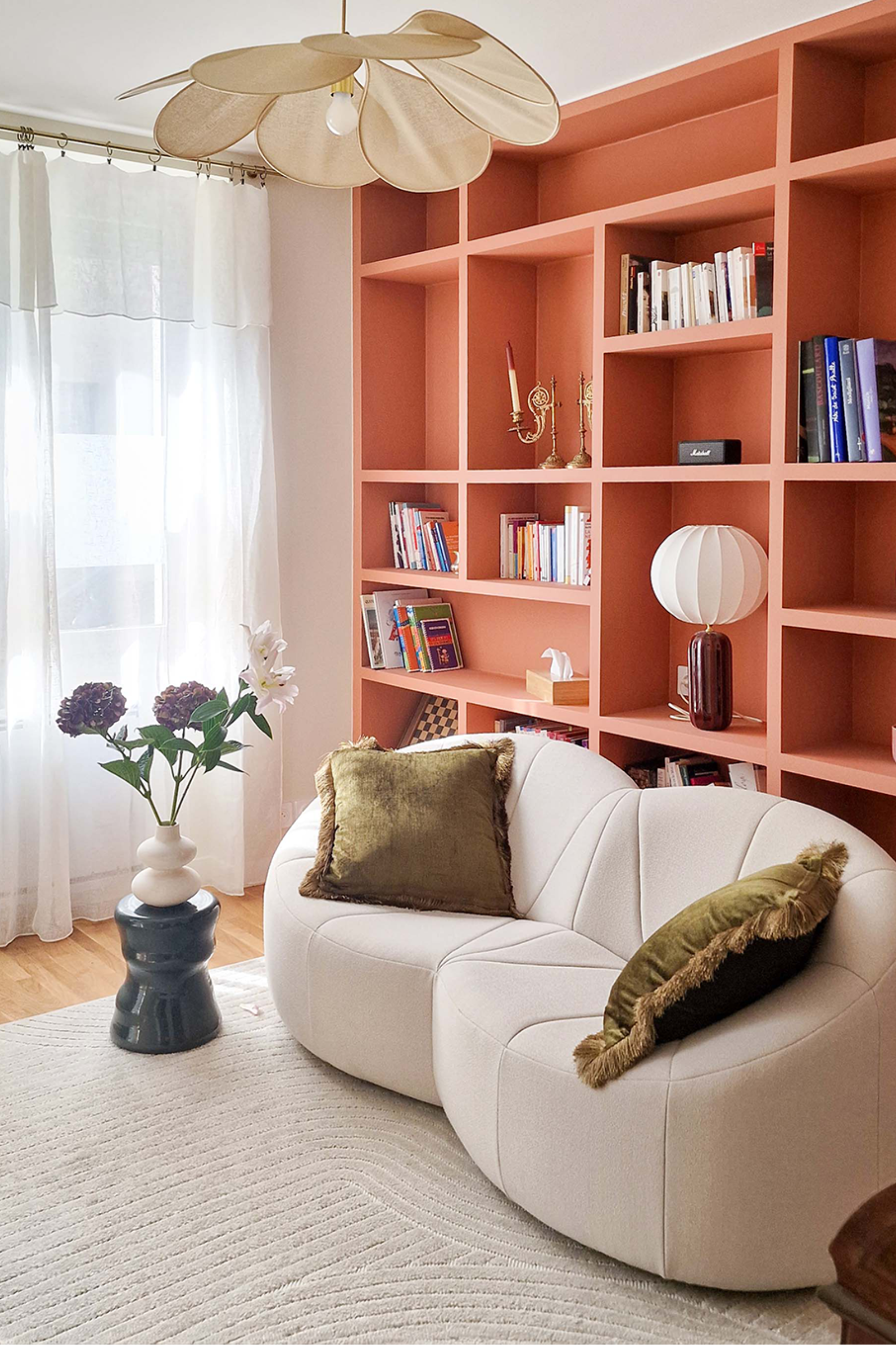 Architecture d'intérieur pour un appartement transformé en cabinet de psychologie à Paris avec bibliothèque sur mesure terracotta, mobilier courbe et design d’intérieur chaleureux pour une salle de consultation apaisante.
