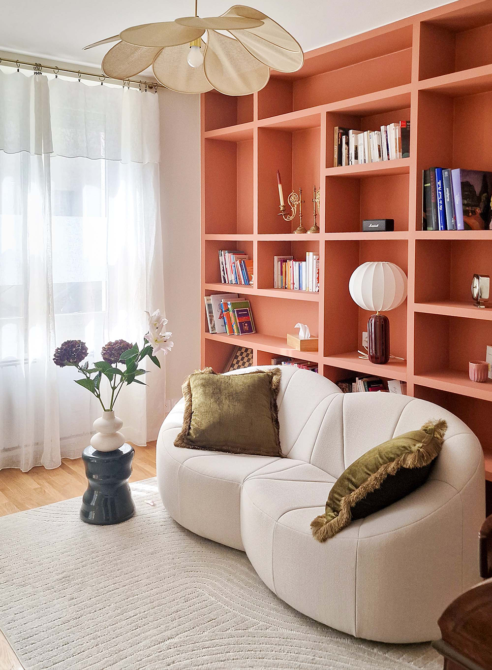 Rénovation d’un appartement en cabinet de psychologie à Paris avec bibliothèque sur mesure terracotta, mobilier courbe et design d’intérieur chaleureux pour une salle de consultation apaisante.