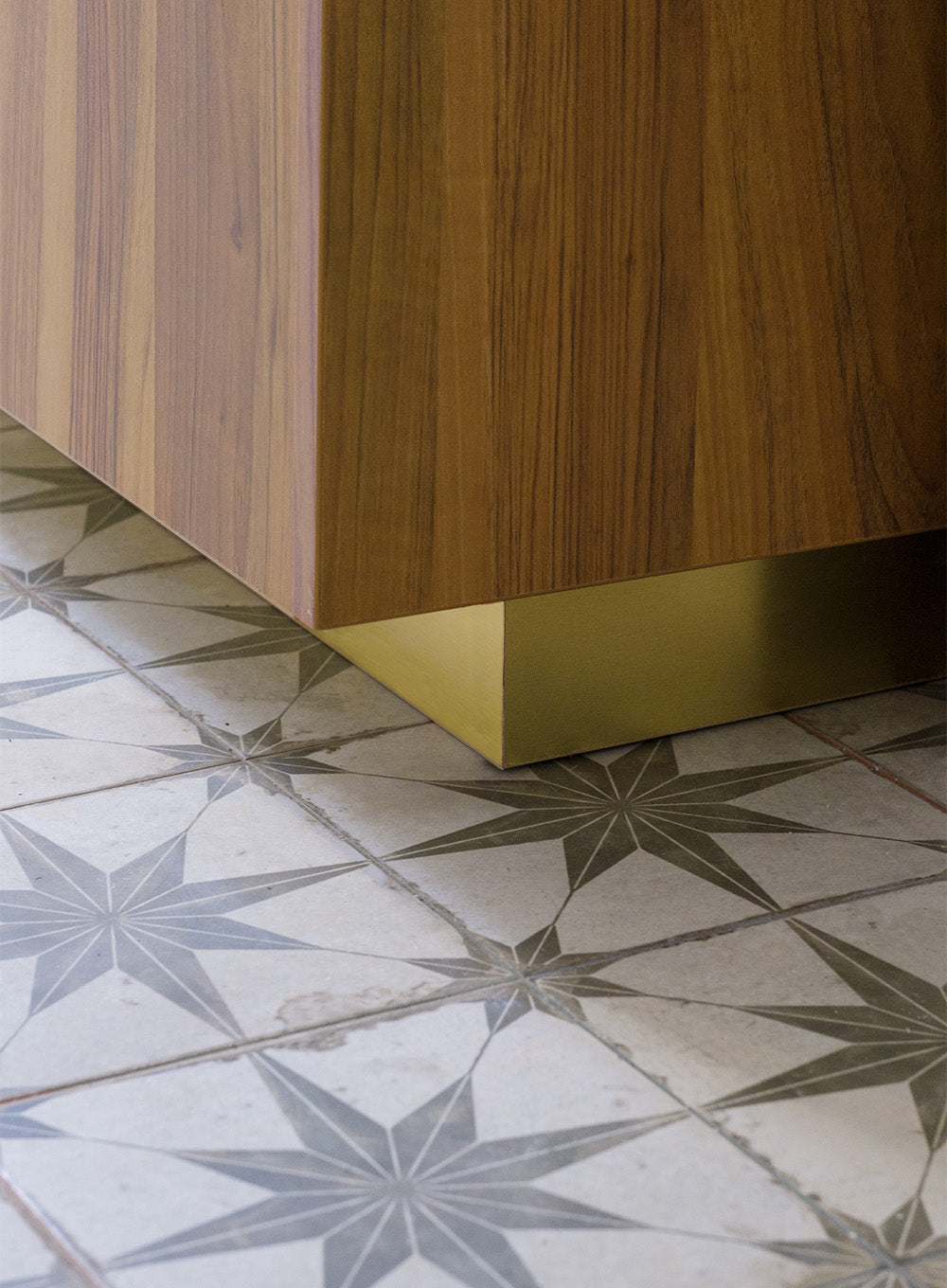 Détail de cuisine sur mesure avec plinthes en laiton doré et carrelage graphique dans un projet d’architecture intérieure à Paris.