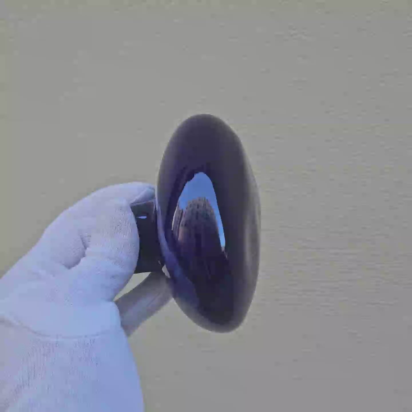 Patère Agate bleu "Sèvres" en porcelaine émaillée, tournée avec un gant blanc pour révéler ses nuances de couleur et ses reflets. #couleur_bleu sèvres