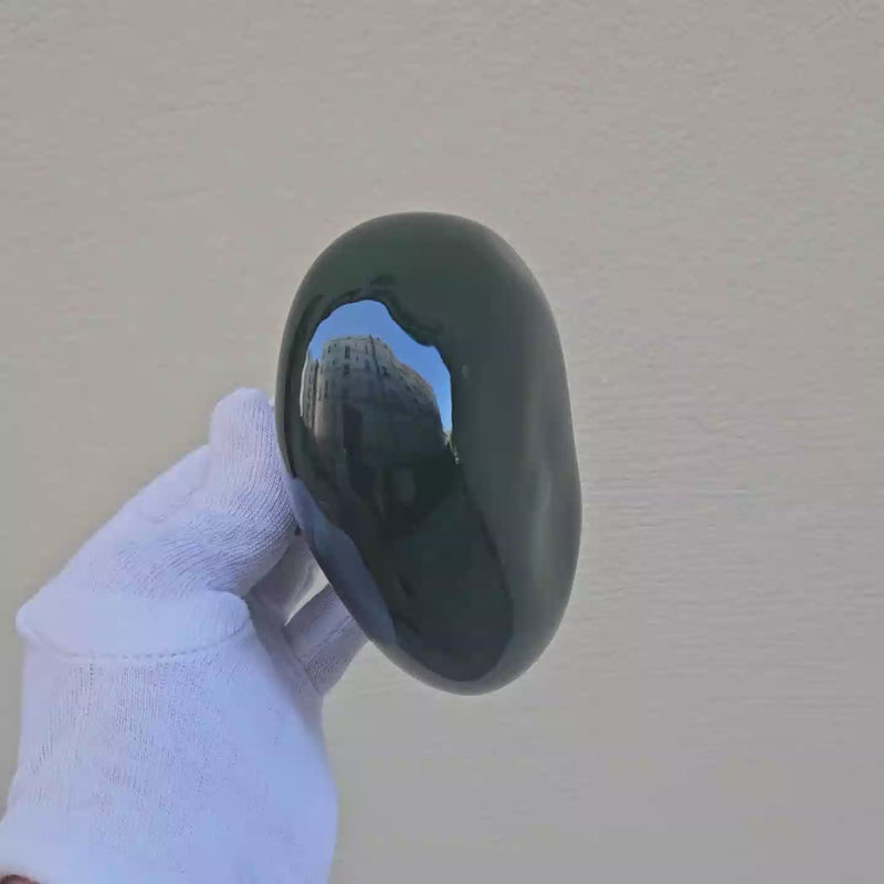 Patère Agate vert Alhambra en porcelaine émaillée, tournée avec un gant blanc pour révéler ses nuances de couleur et ses reflets. #couleur_vert alhambra