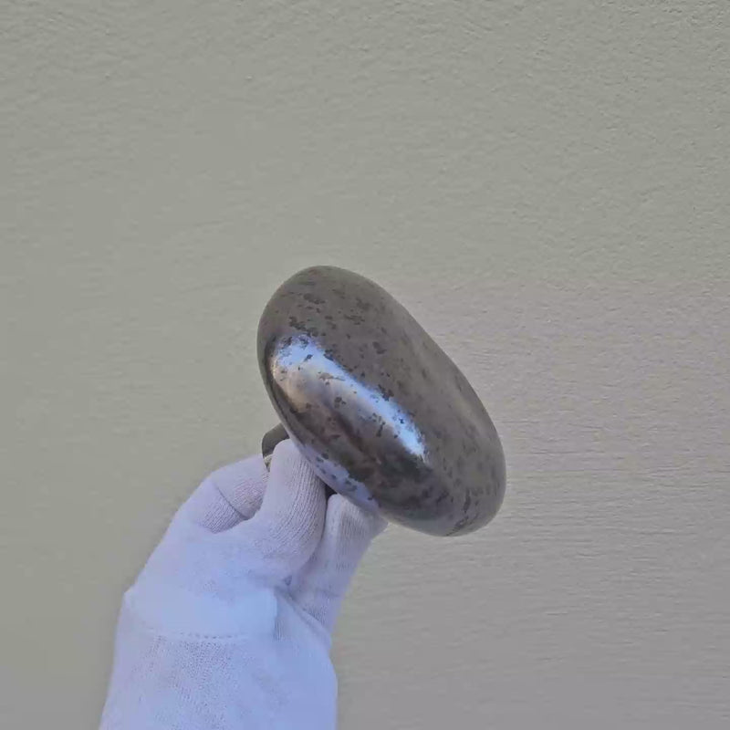 Patère Agate métallisée en porcelaine émaillée, tournée avec un gant blanc pour révéler ses nuances de couleur et ses reflets. #couleur_métallique