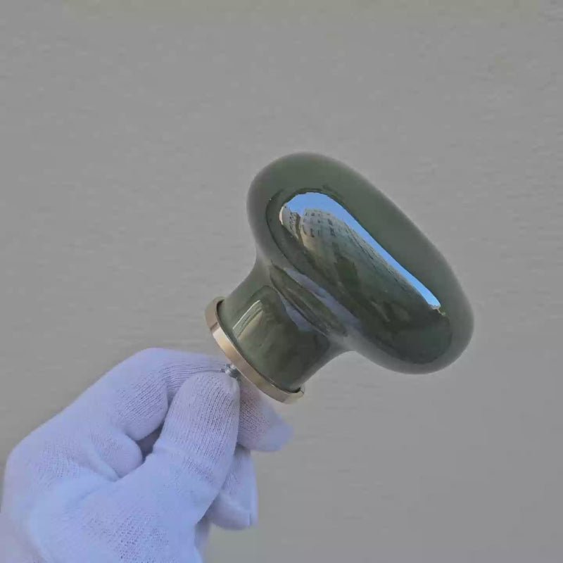 Patère Agate vert Mousse  en porcelaine émaillée, tournée avec un gant blanc pour révéler ses nuances de couleur et ses reflets. #couleur_vert mousse