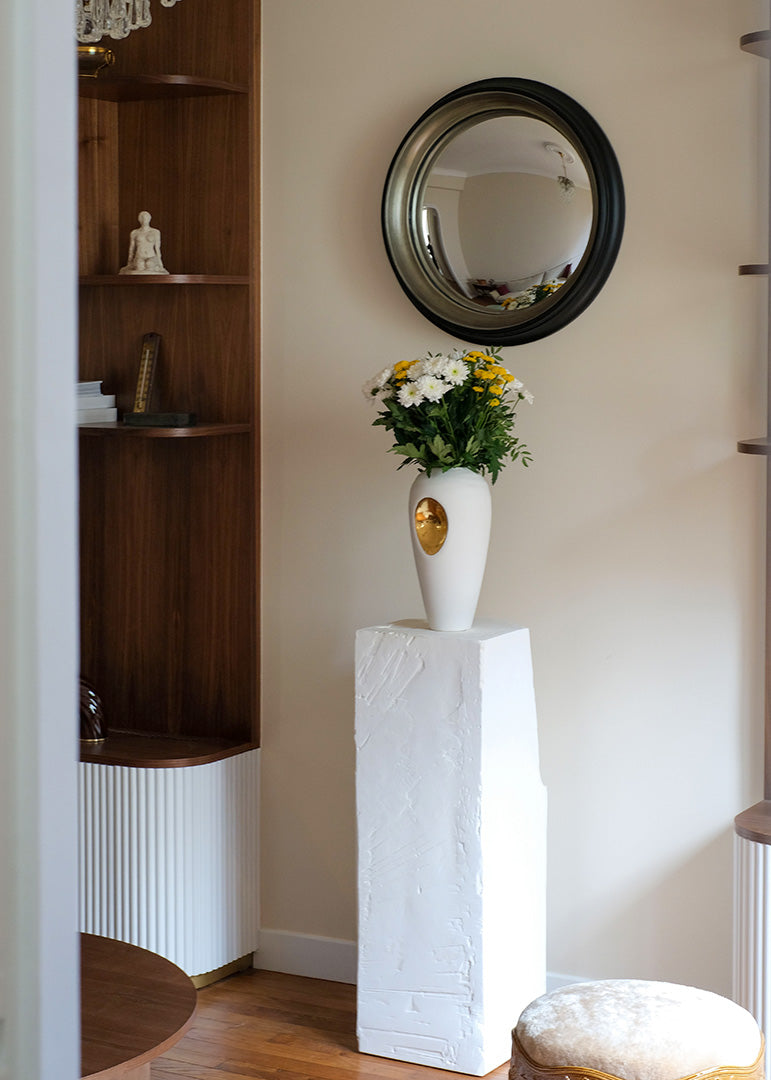 Projet d’architecture d’intérieur à Saint Mandé. Détail du salon avec miroir convexe pensé pour agrandir visuellement l’espace, mobilier intégré et vase en céramique crée sur mesure.