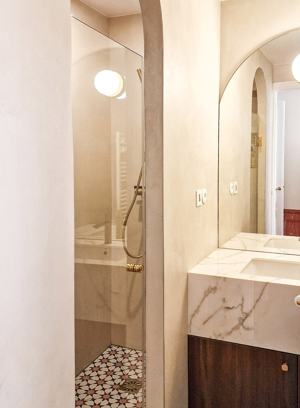 Salle de bain rénovée à Saint Mandé avec béton ciré, meuble vasque en noyer, détails en laiton et surface en marbre pour un design d’intérieur sensoriel.