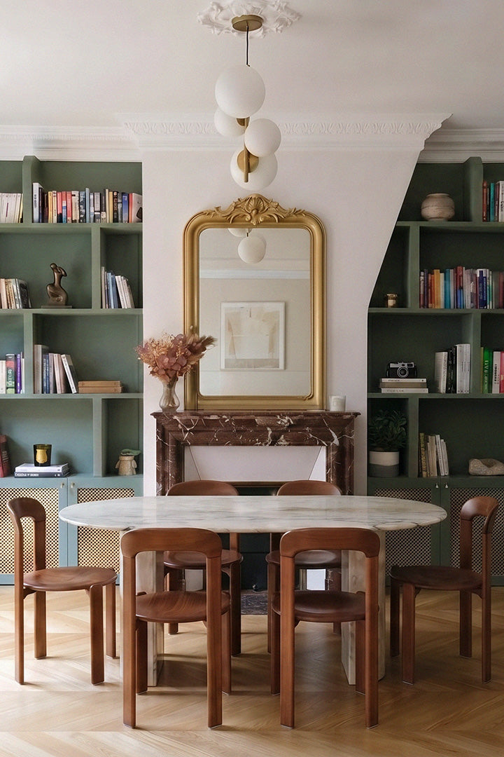 Salle à manger d'un appartement haussmannien parisien, projet Convention par Ombre d'Or : architecture d'intérieur sur mesure avec table en marbre, miroir doré et bibliothèque vert sauge.