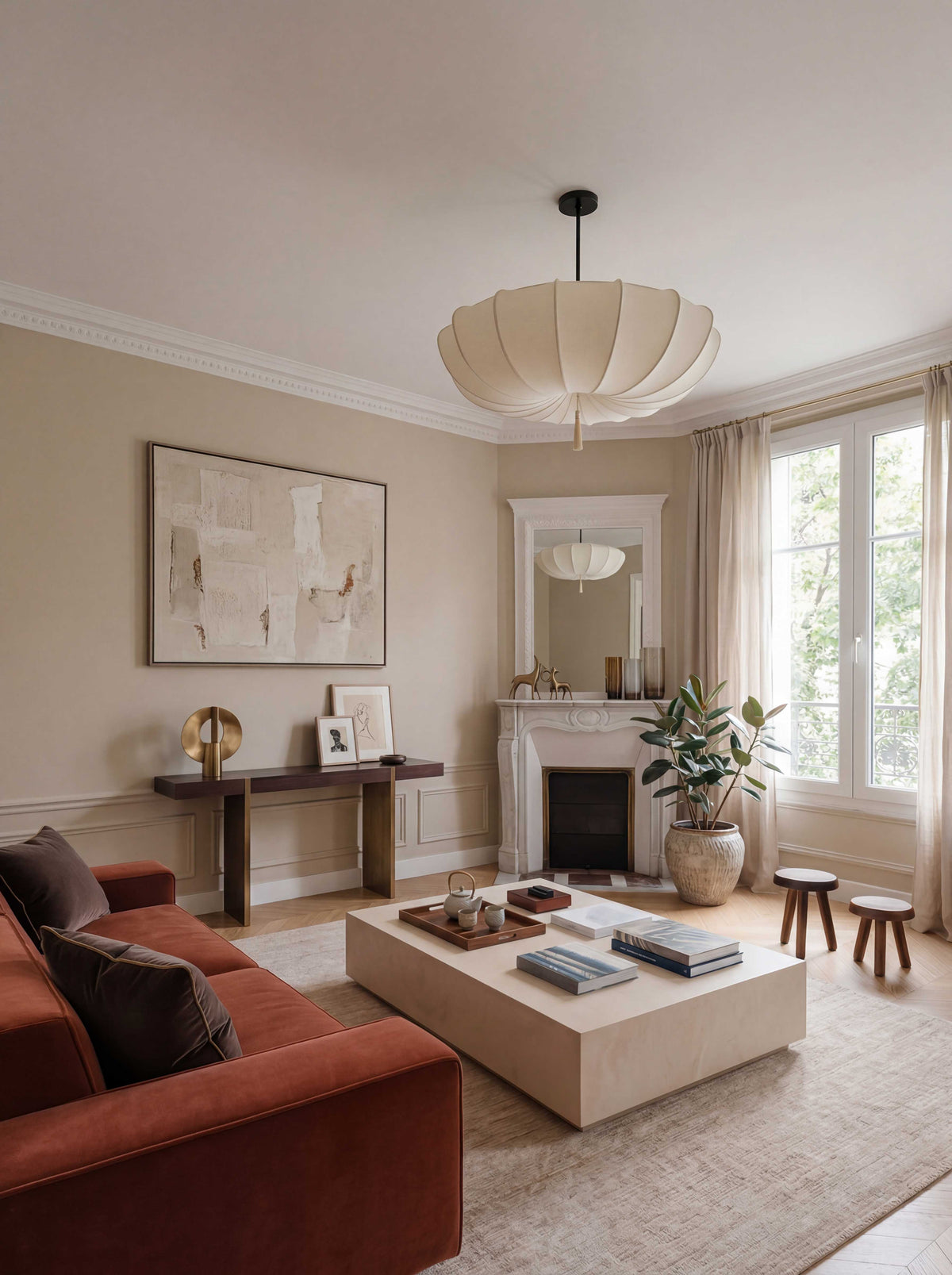Salon d'un appartement haussmannien parisien, projet Convention par Ombre d'Or : canapé velours terracotta, cheminée d'origine en marbre, table basse sculpturale et suspension contemporaine plissée.