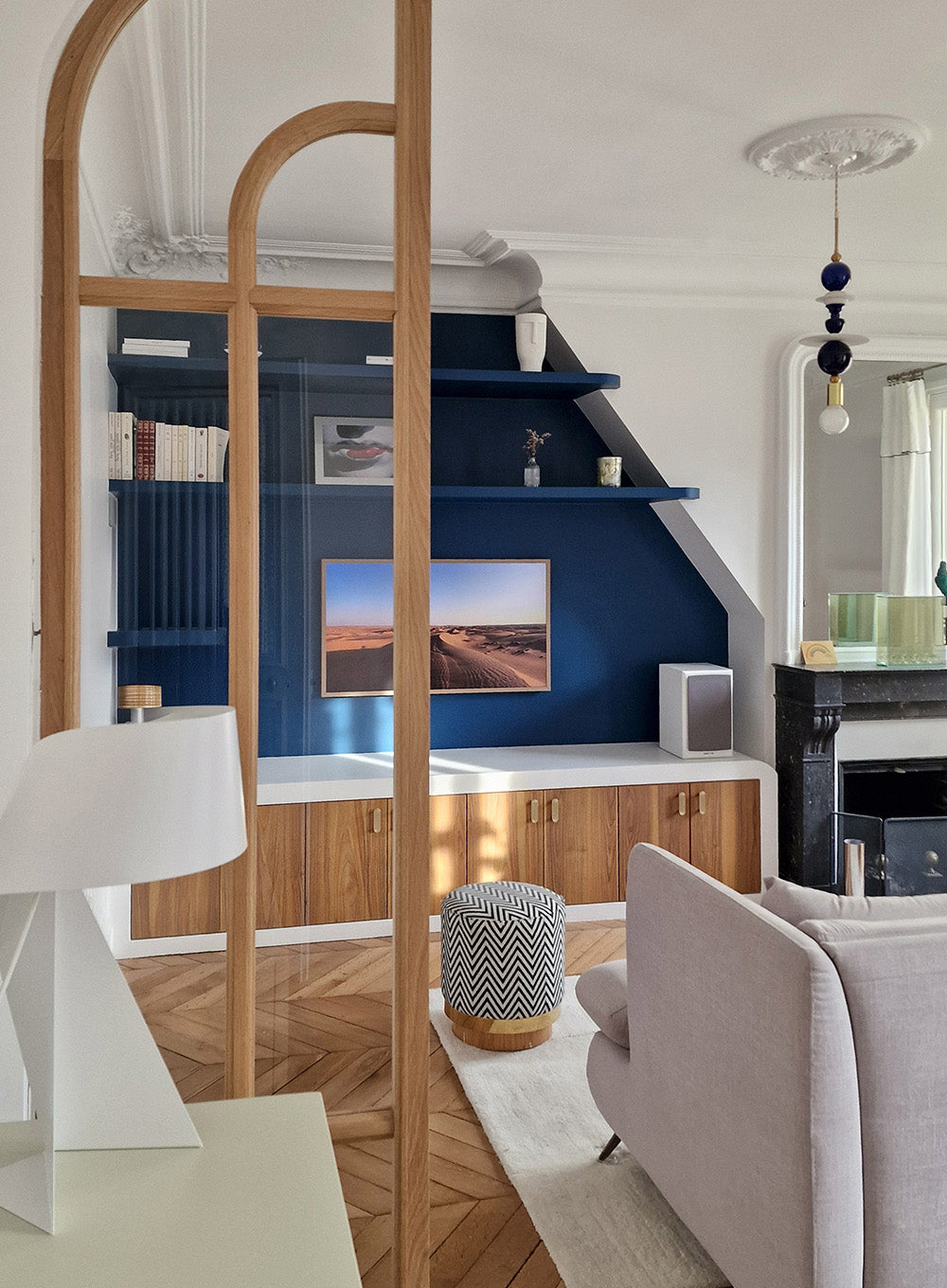 Détail d’une verrière sur mesure en bois intégrée dans un salon mêlant bois, parquet à chevrons, moulures et teintes de bleu profond pour un projet d'architecture d'intérieur à Paris.